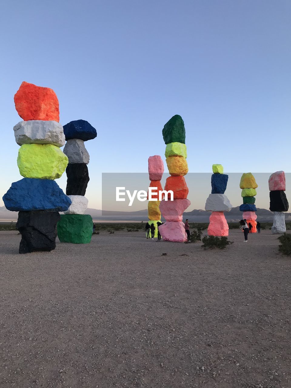 People by multi colored rocks stacked on land against sky