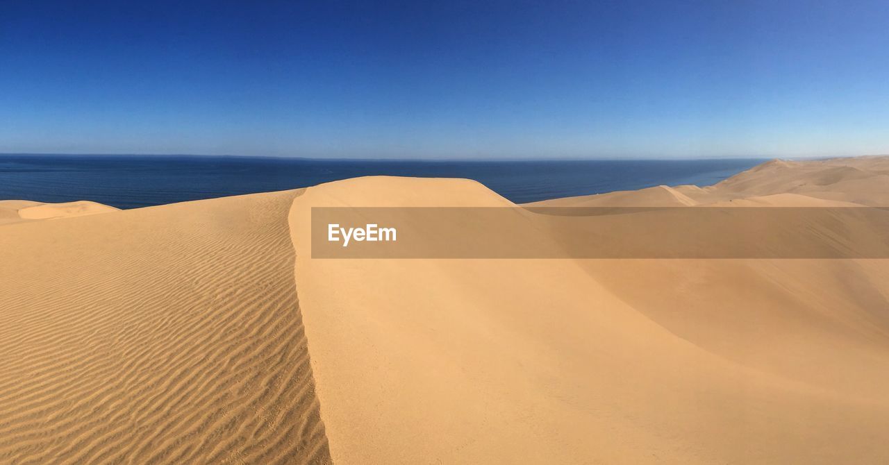 Scenic view of sand dunes against sea