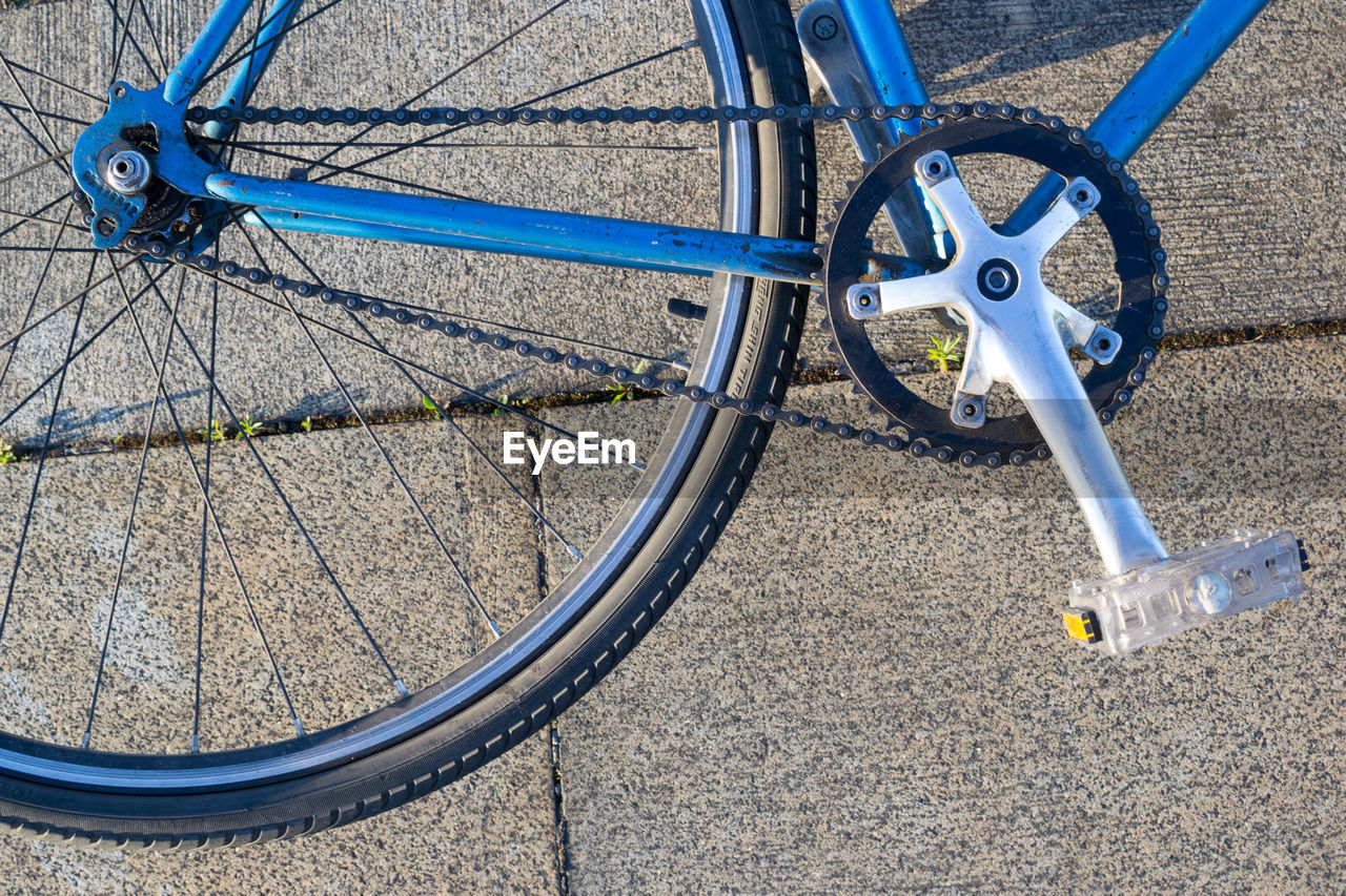 Close-up of chain and sprocket on blue bicycle frame