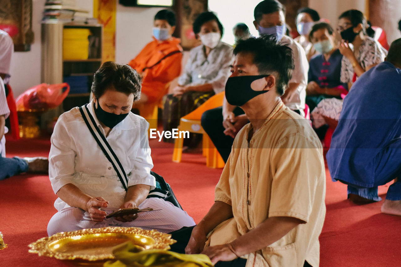 People wearing mask sitting at temple