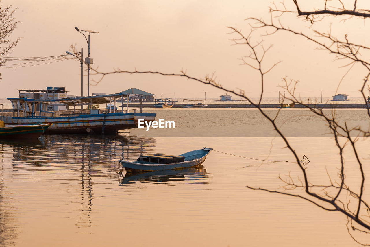 Boat moored in lake against sky during sunset