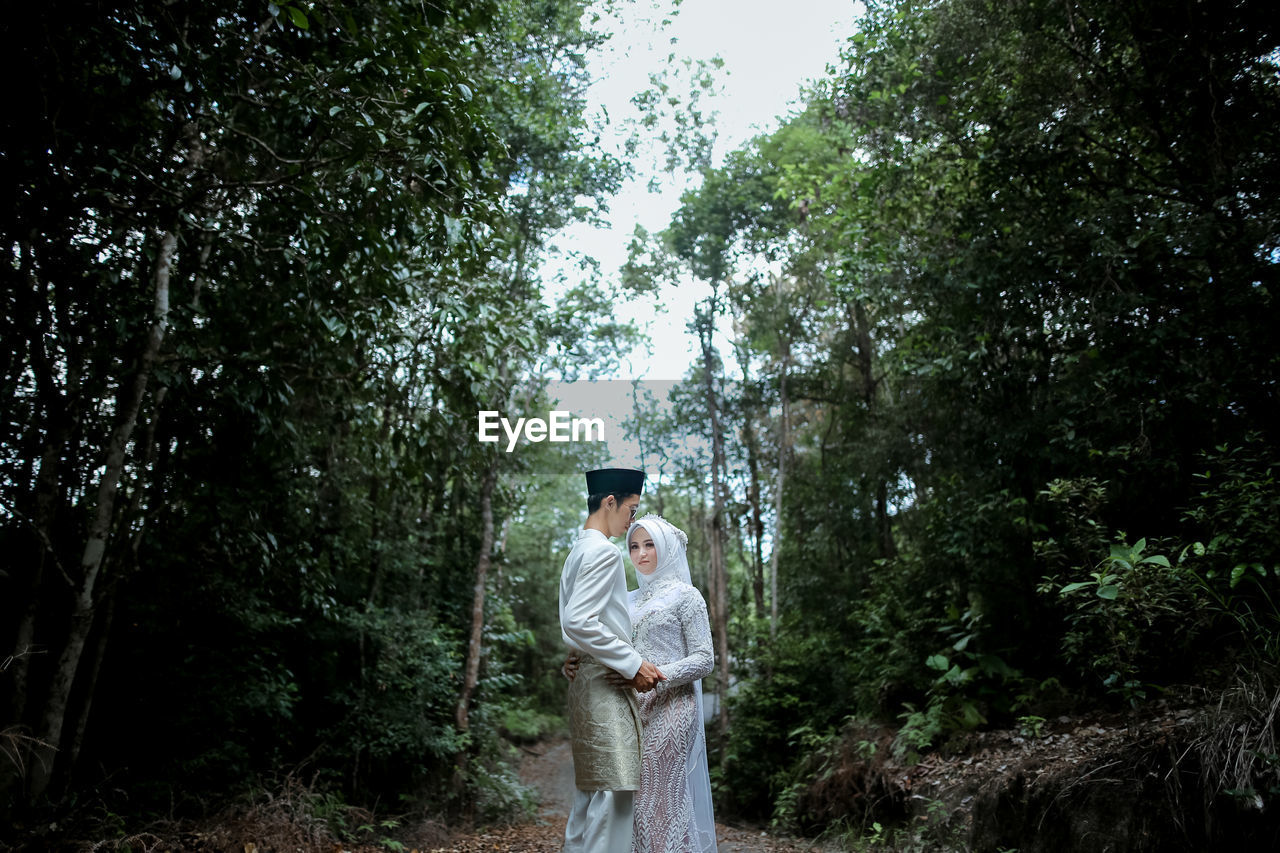 Couple standing amidst trees in forest