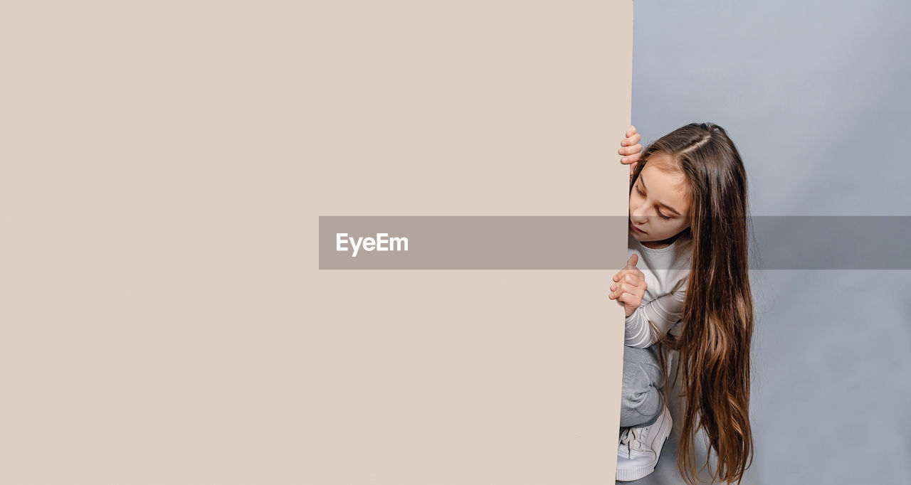 Large sheet of white cardboard. llittle girl and empty banner. advertising.