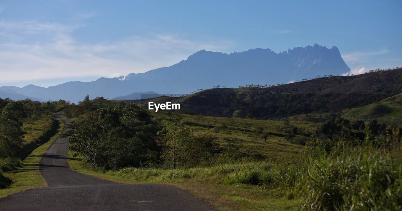 Scenic view of road by mountains against sky