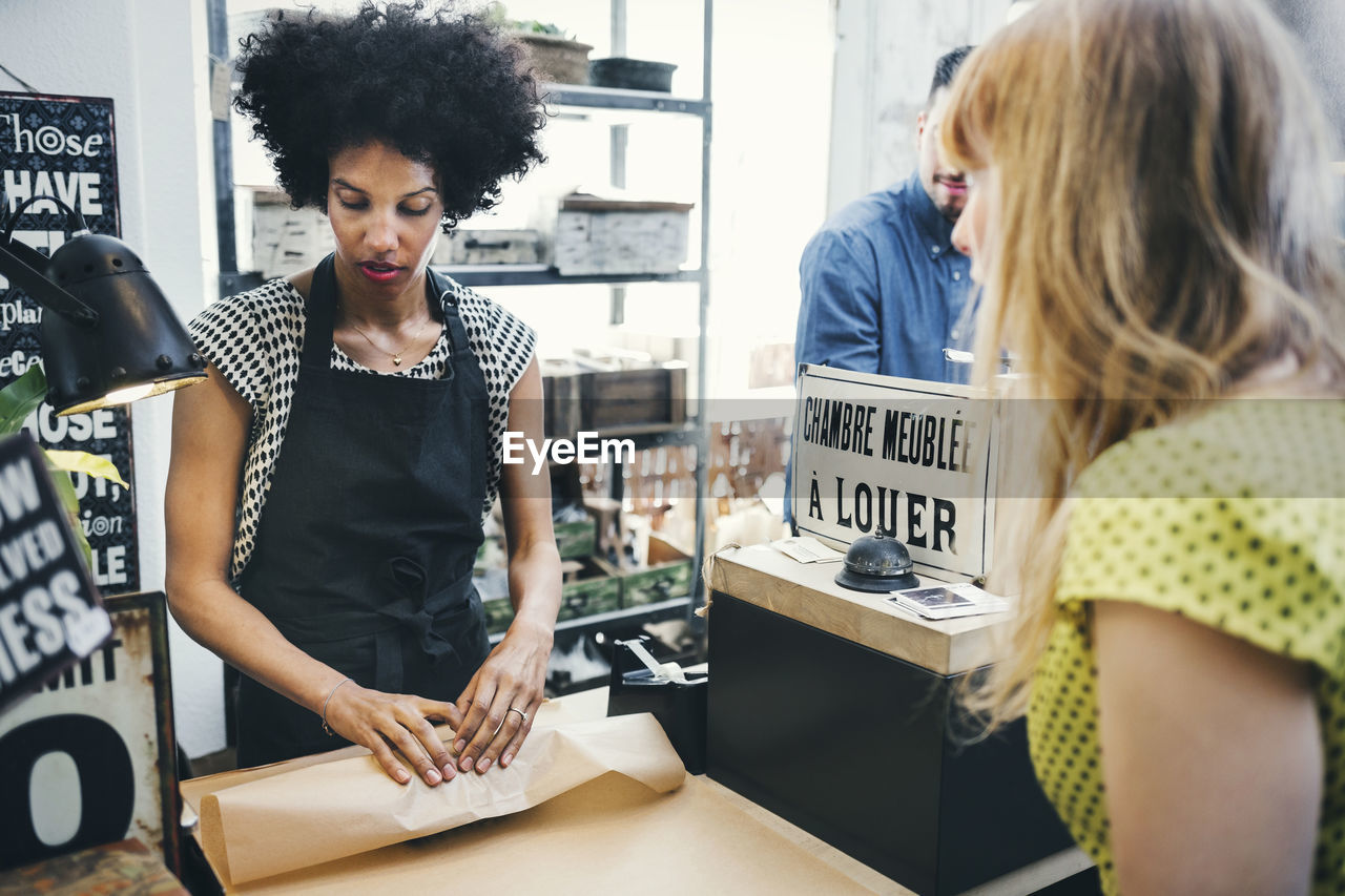 Mid adult woman packing vase for customer in store