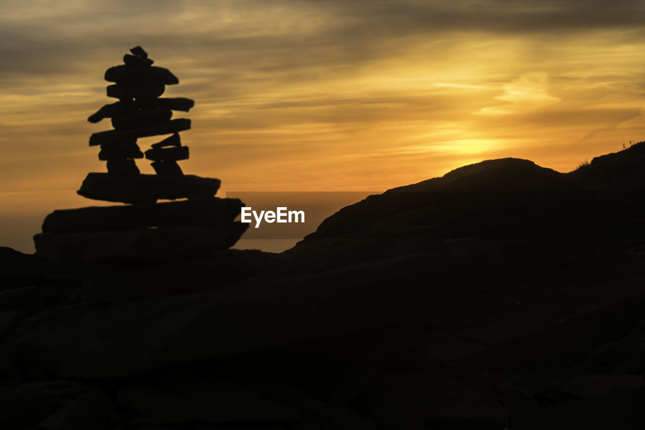 STACK OF ROCKS IN MOUNTAIN AGAINST SUNSET SKY