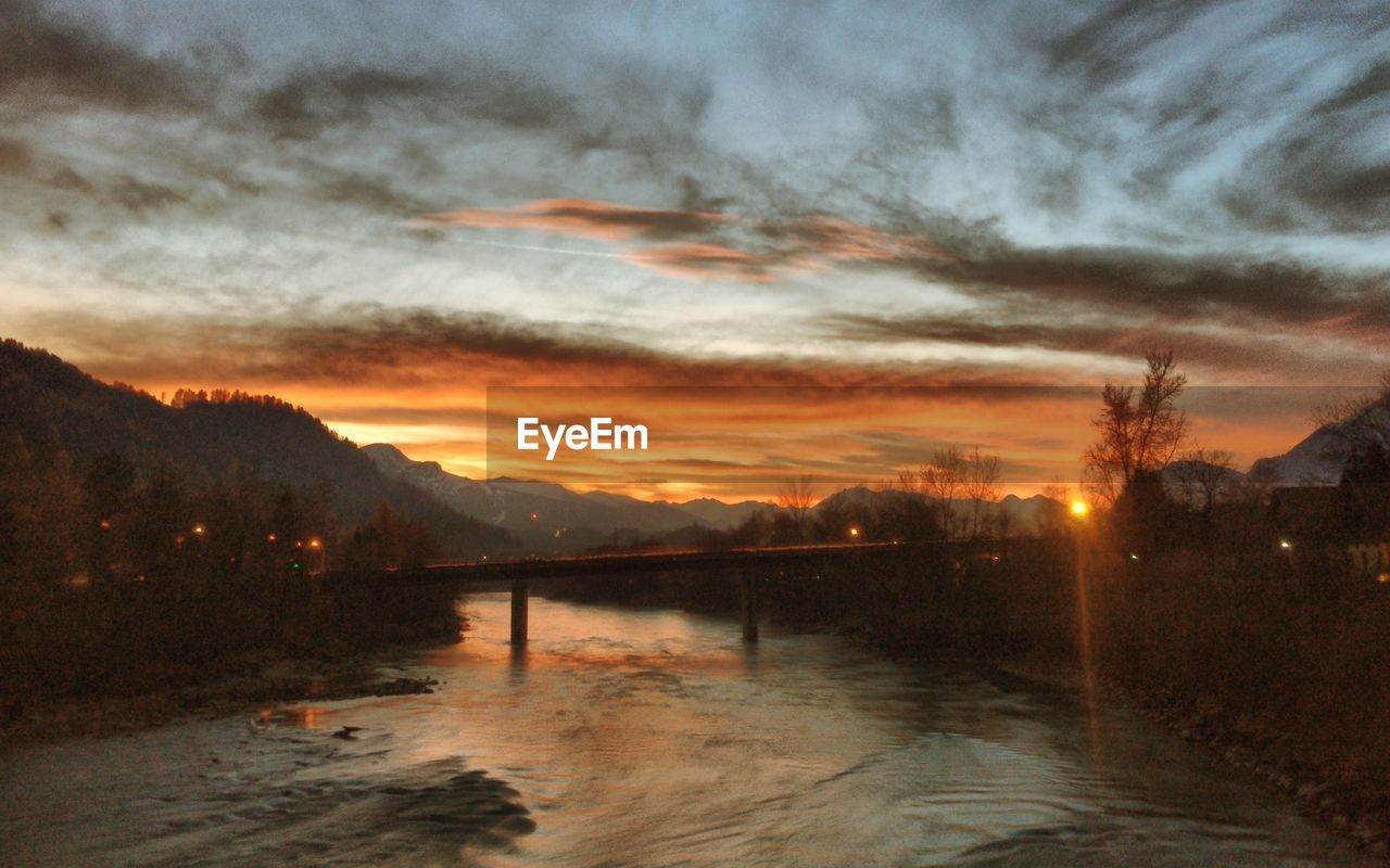 Bridge over river against cloudy sky during sunset