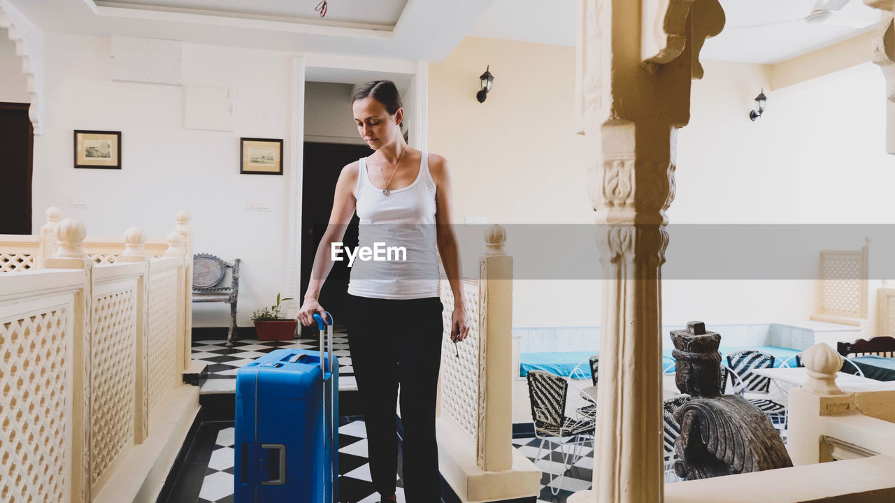 Woman carrying suitcase at hotel