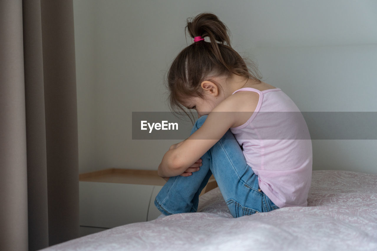 Girl sitting on bed at home