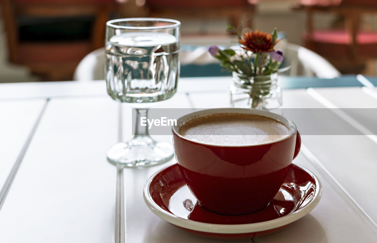 CLOSE-UP OF COFFEE CUP ON GLASS TABLE