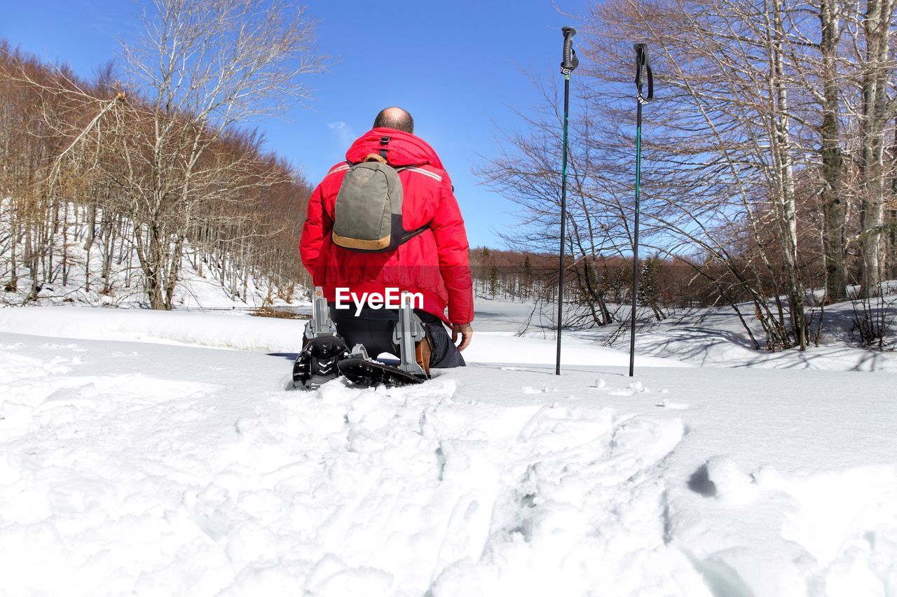 REAR VIEW OF MAN ON SNOW COVERED LAND