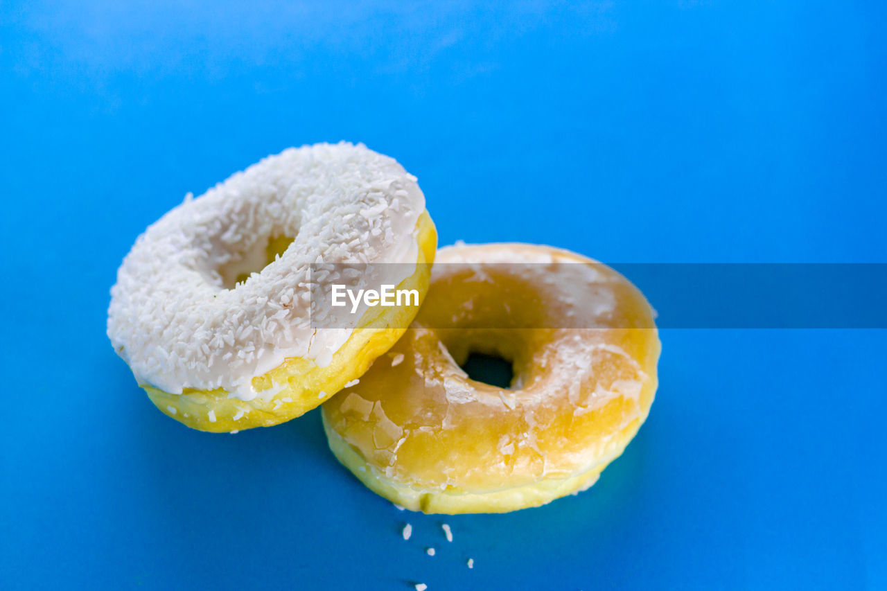 Two pieces of donut on blue background isolate with copy space