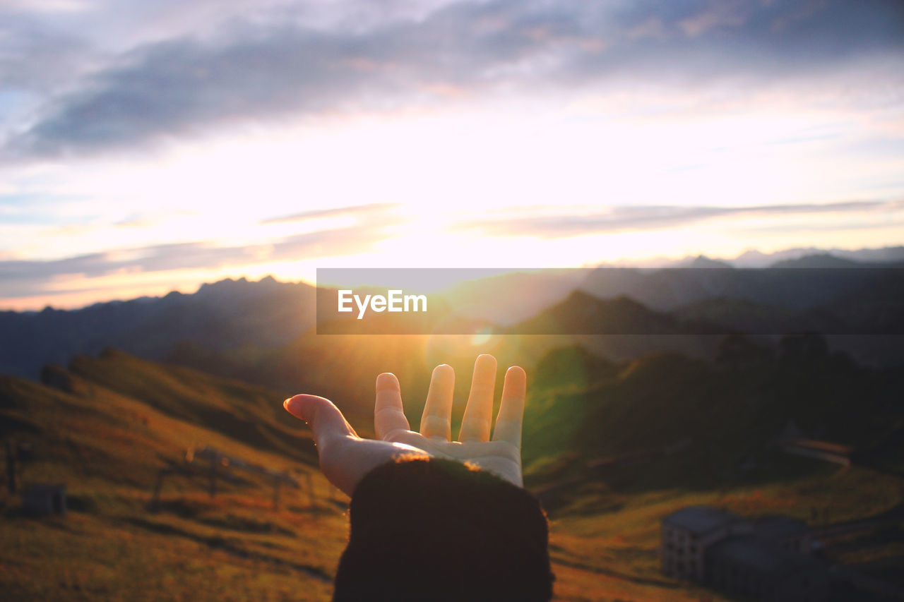 Hand outstretched towards scenic view of mountains