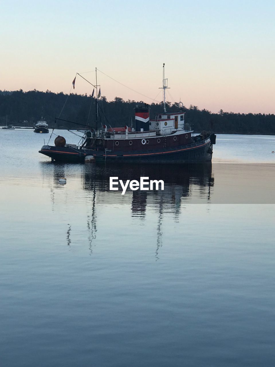 Boats sailing in sea against clear sky during sunset