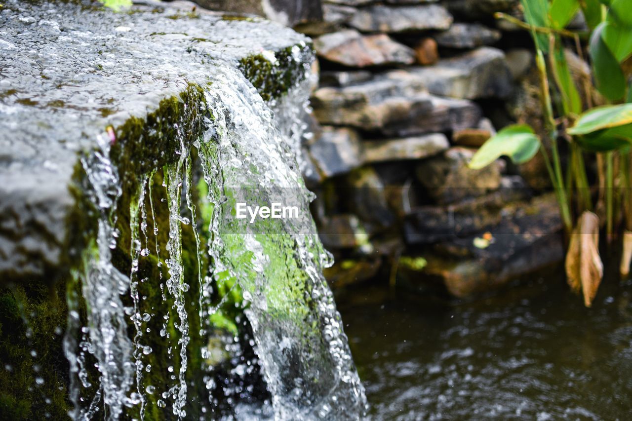 CLOSE-UP OF WATERFALL AGAINST ROCKS