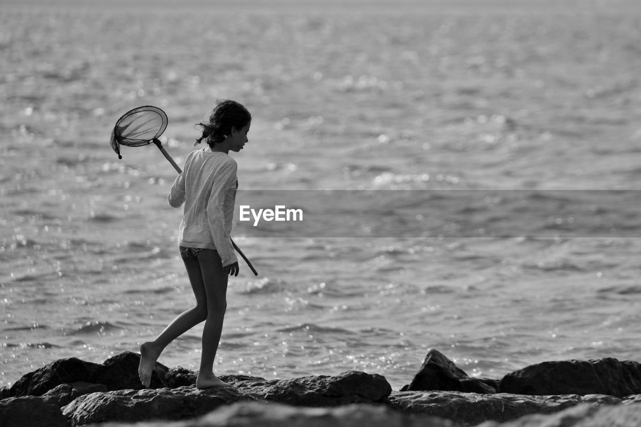 Side view of girl carrying butterfly net on shore