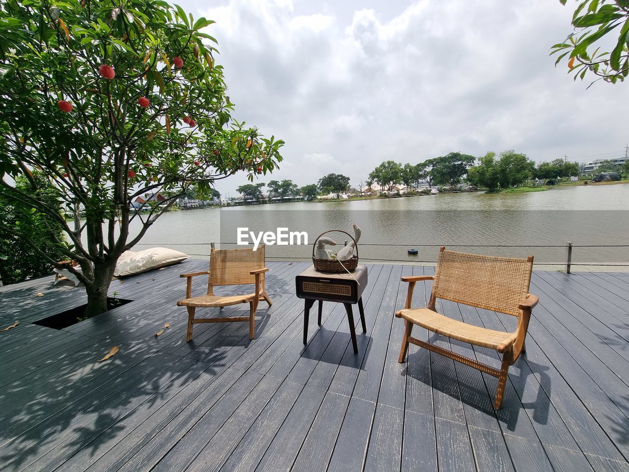 water, nature, tree, seat, tranquility, plant, relaxation, sky, table, wood, chair, beauty in nature, tranquil scene, cloud, scenics - nature, no people, summer, trip, travel destinations, lake, vacation, holiday, idyllic, furniture, deck, architecture, outdoors, absence, beach, estate, travel, day, empty, bench, land, environment, food and drink, tourism, landscape, luxury, tropical climate, wealth, walkway