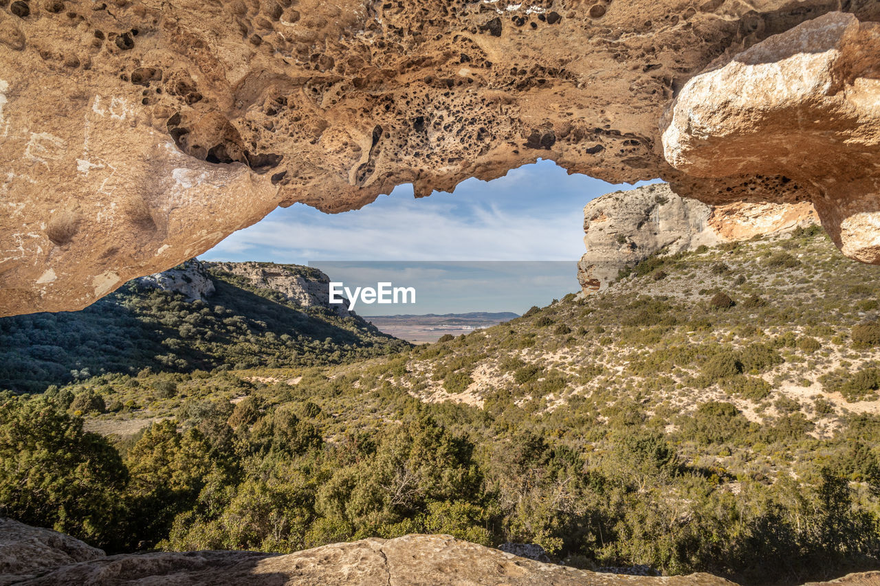 rock, nature, rock formation, scenics - nature, beauty in nature, sky, landscape, environment, land, tranquility, travel destinations, geology, non-urban scene, travel, no people, sunlight, wadi, plant, mountain, day, physical geography, outdoors, cloud, tranquil scene, sunny, idyllic, eroded, architecture, valley, arch, outdoor pursuit, leisure activity, tree, extreme terrain, desert, tourism, activity, natural arch, water, clear sky, semi-arid, cave, terrain, formation, remote, arid climate