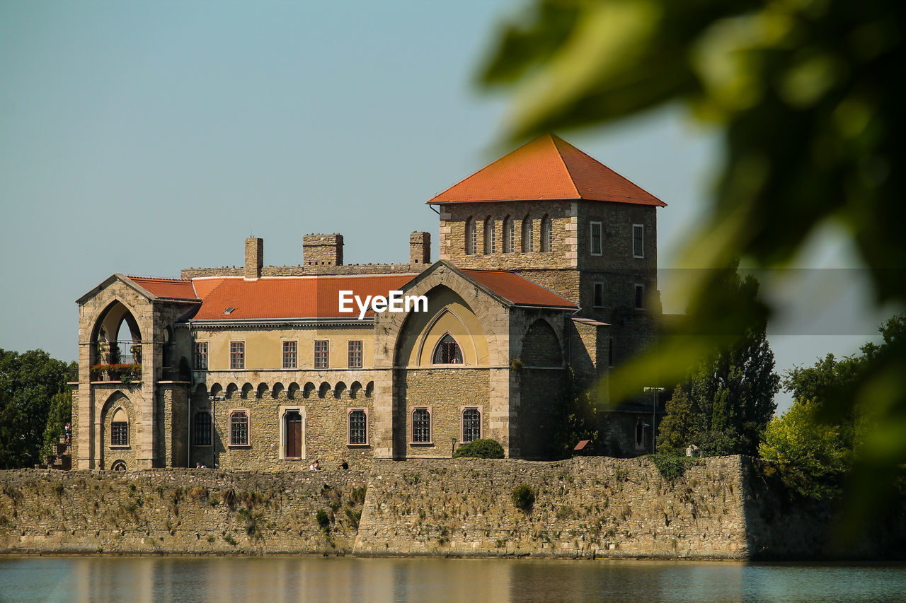 Castle by trees against clear sky