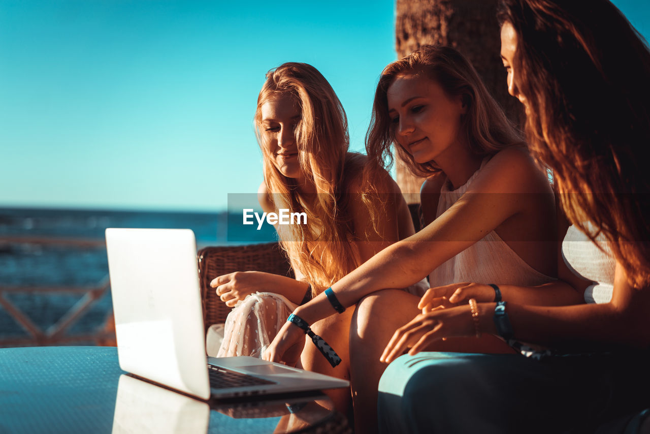 Close-up of young women using laptop at beach