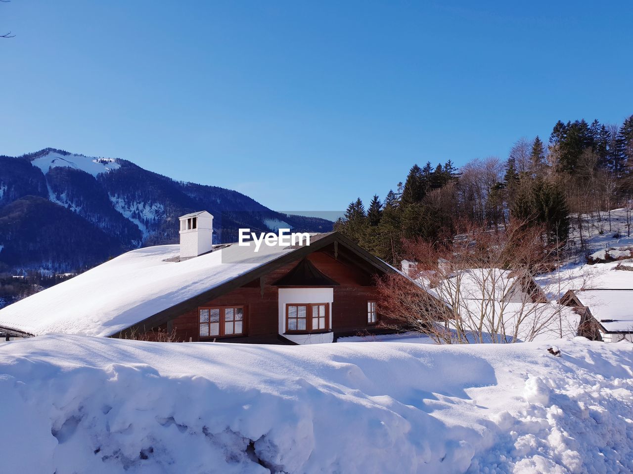 Houses on snow covered landscape against clear blue sky