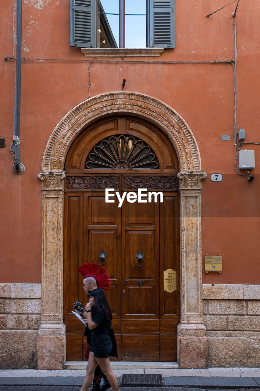 FULL LENGTH OF WOMAN STANDING BY DOOR OF BUILDING