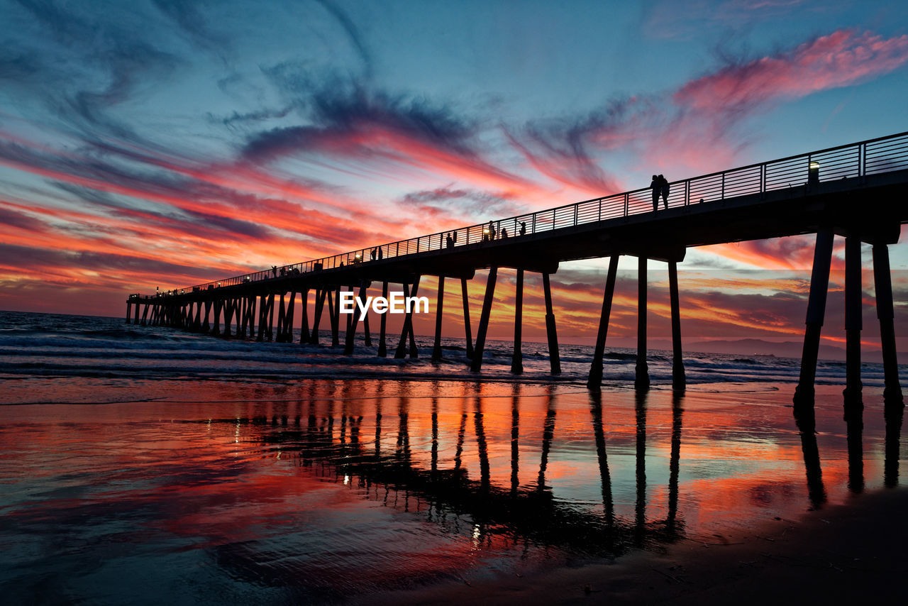 Silhouette pier at beach against sky during sunset