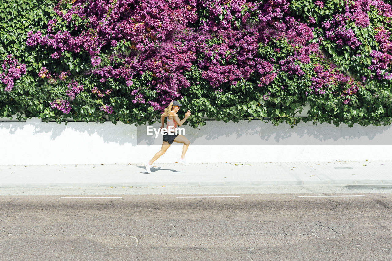 Woman jogging on street , with colorful flowers background
