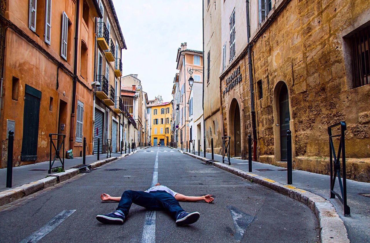 Man sleeping on street amidst buildings in city