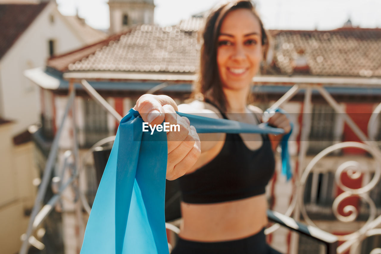 Young sporty fit woman exercising with elastic bands on her rooftop