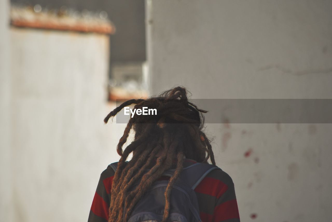 Rear view of man walking against houses