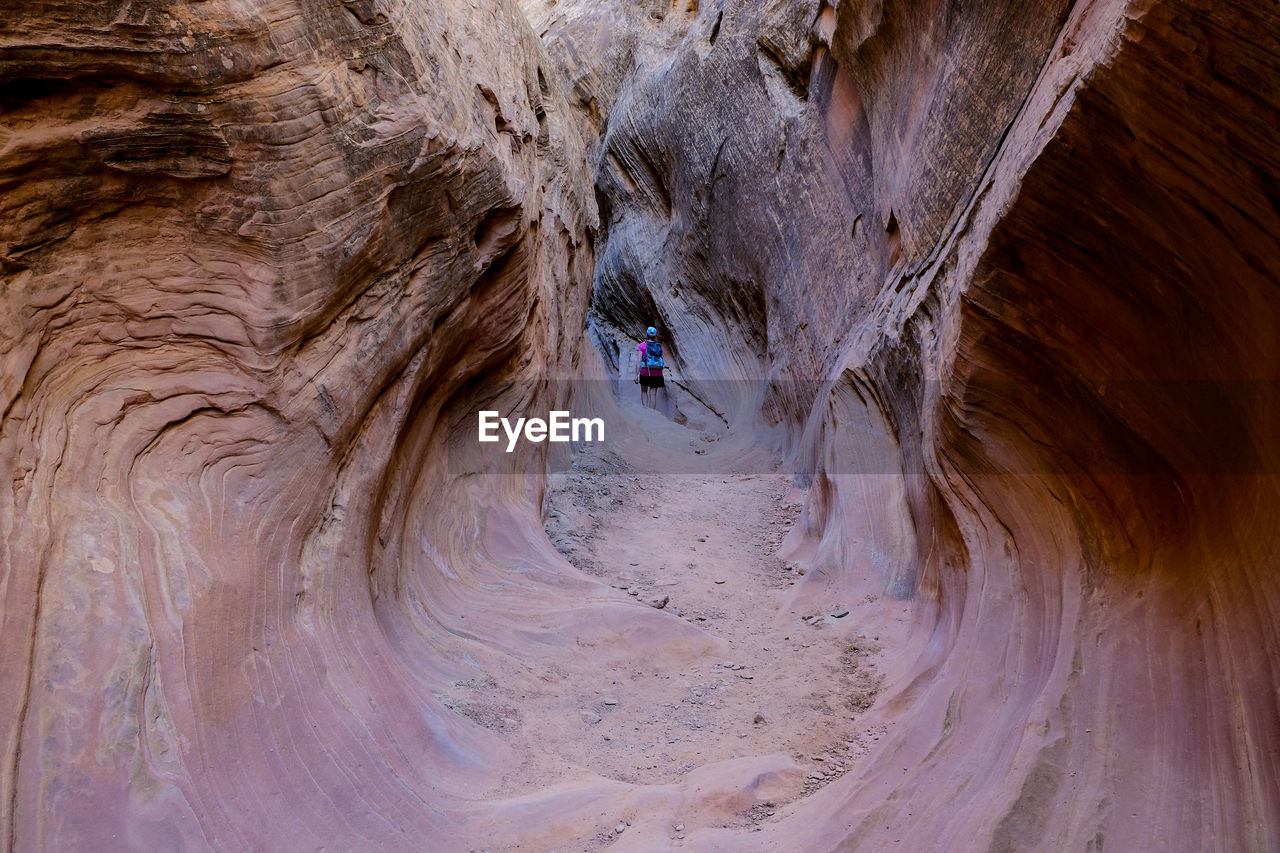 Rear view of mid adult woman standing amidst rock formation in cave