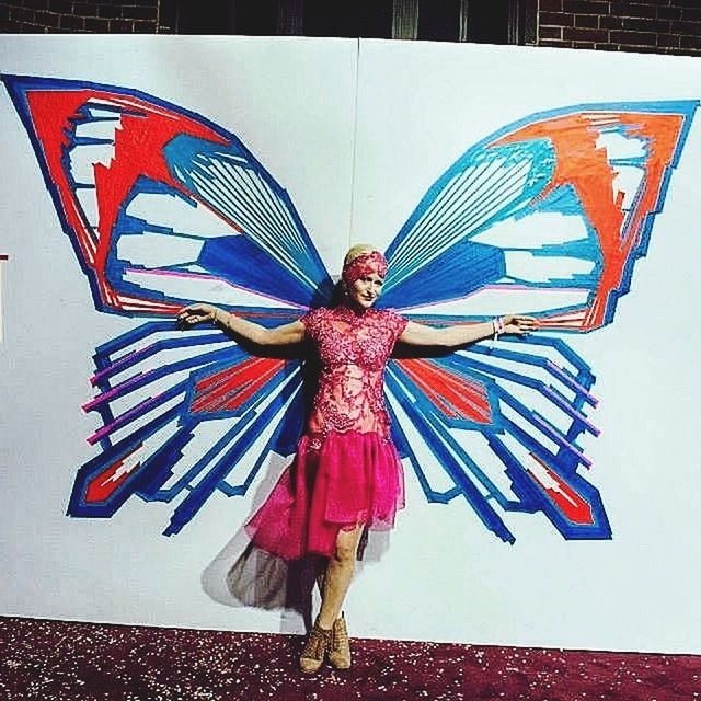 Full length portrait of woman standing against butterfly painting