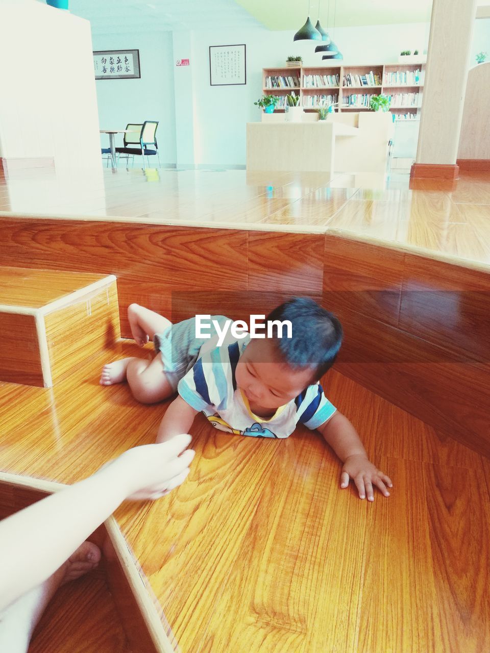 HIGH ANGLE VIEW OF GIRL LYING ON HARDWOOD FLOOR AT HOME