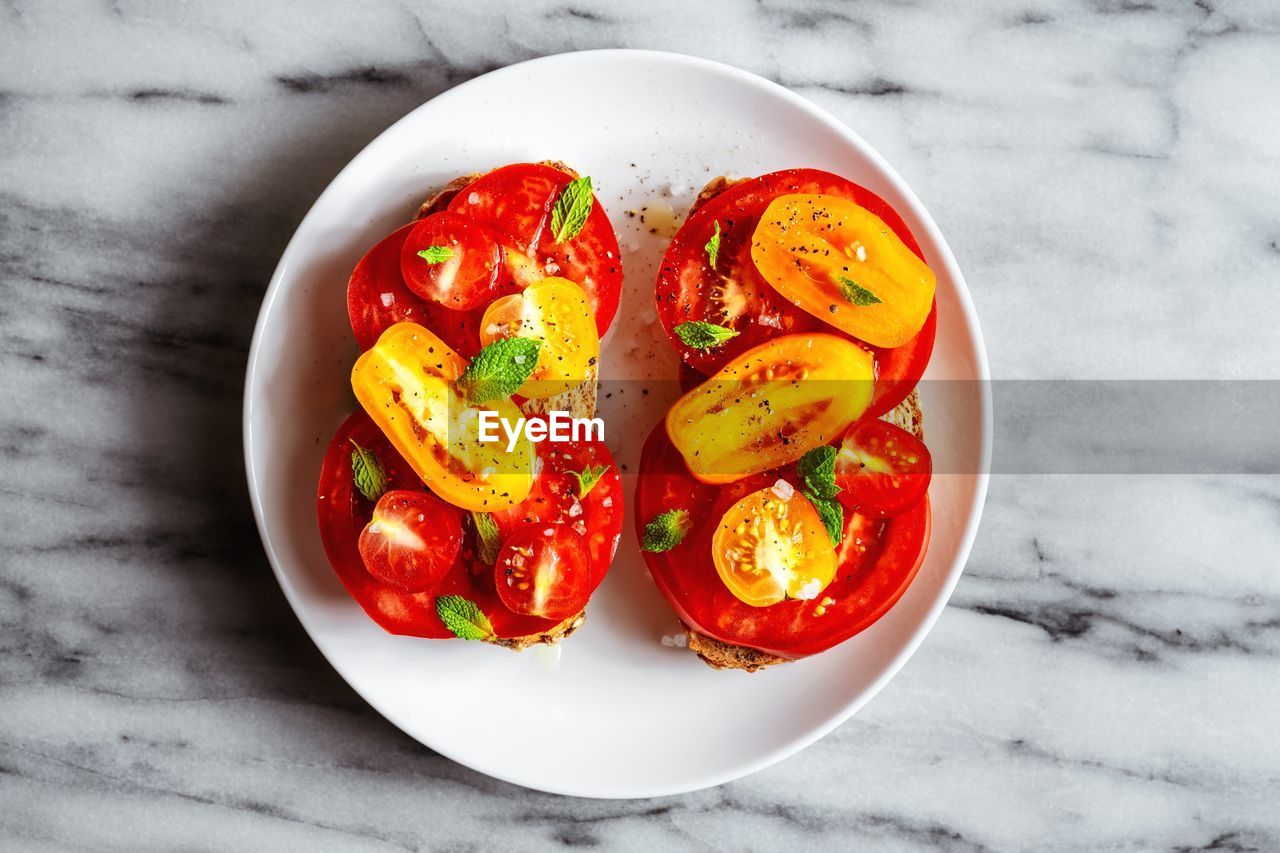 Tomato open sandwiches on a plate on marble surface