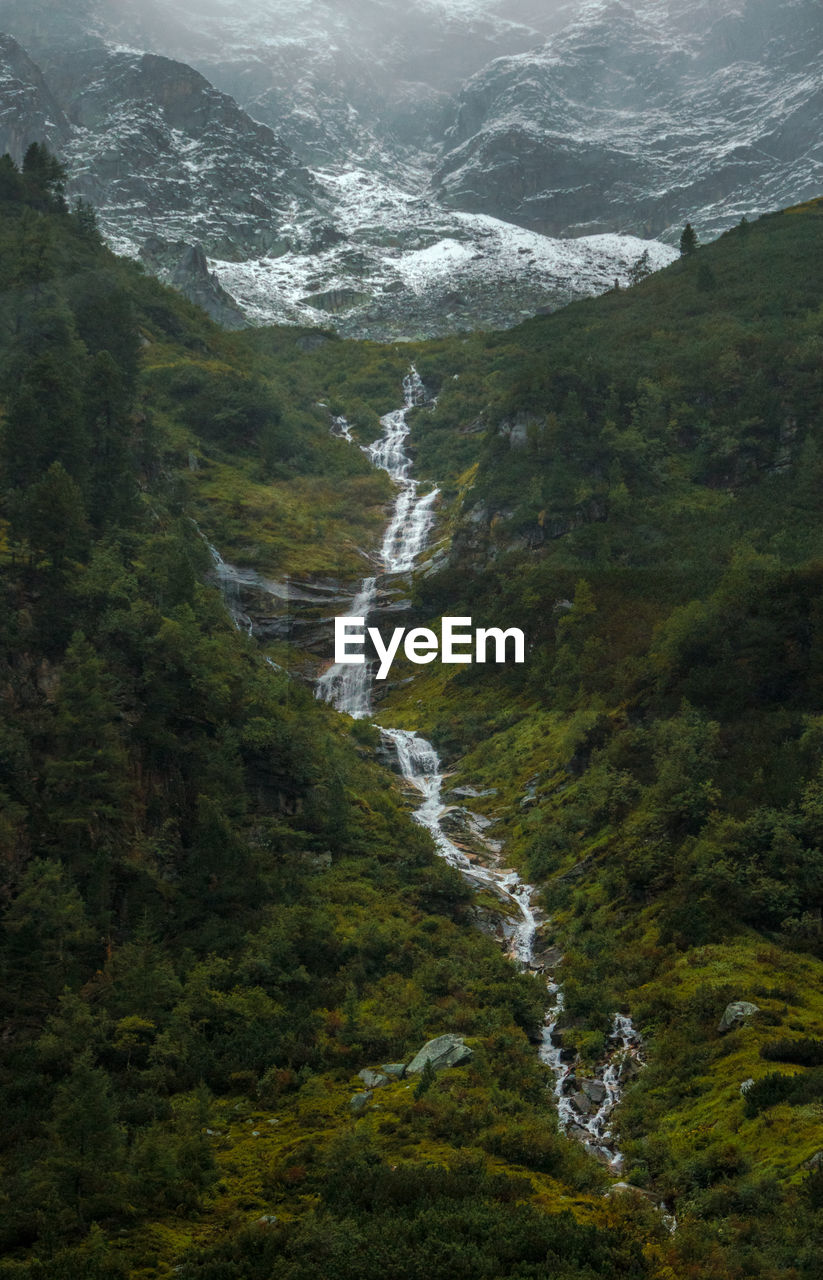 Scenic view of waterfall in mountains and forest - mittersill, austria