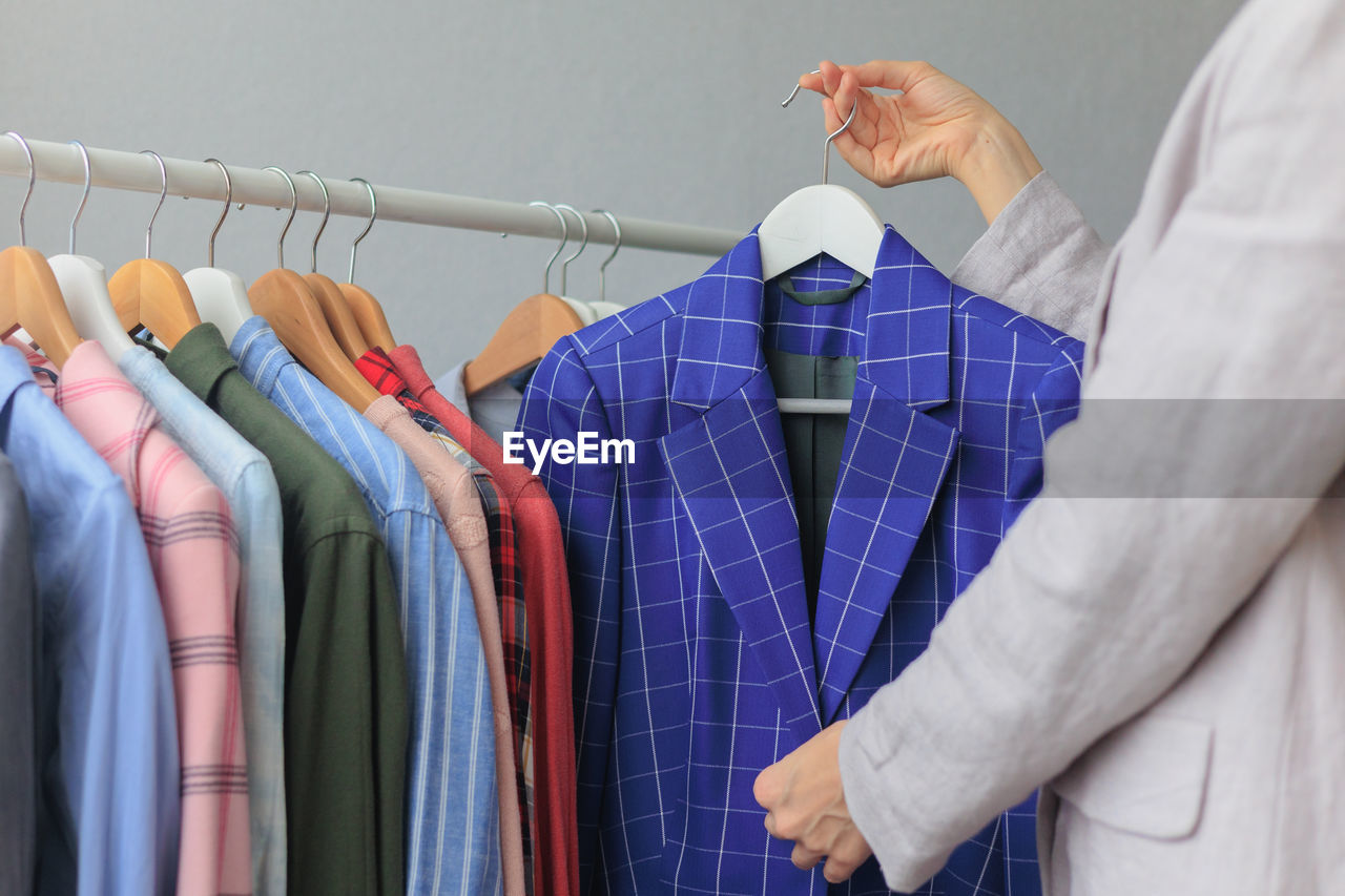 midsection of man with clothes hanging on rack