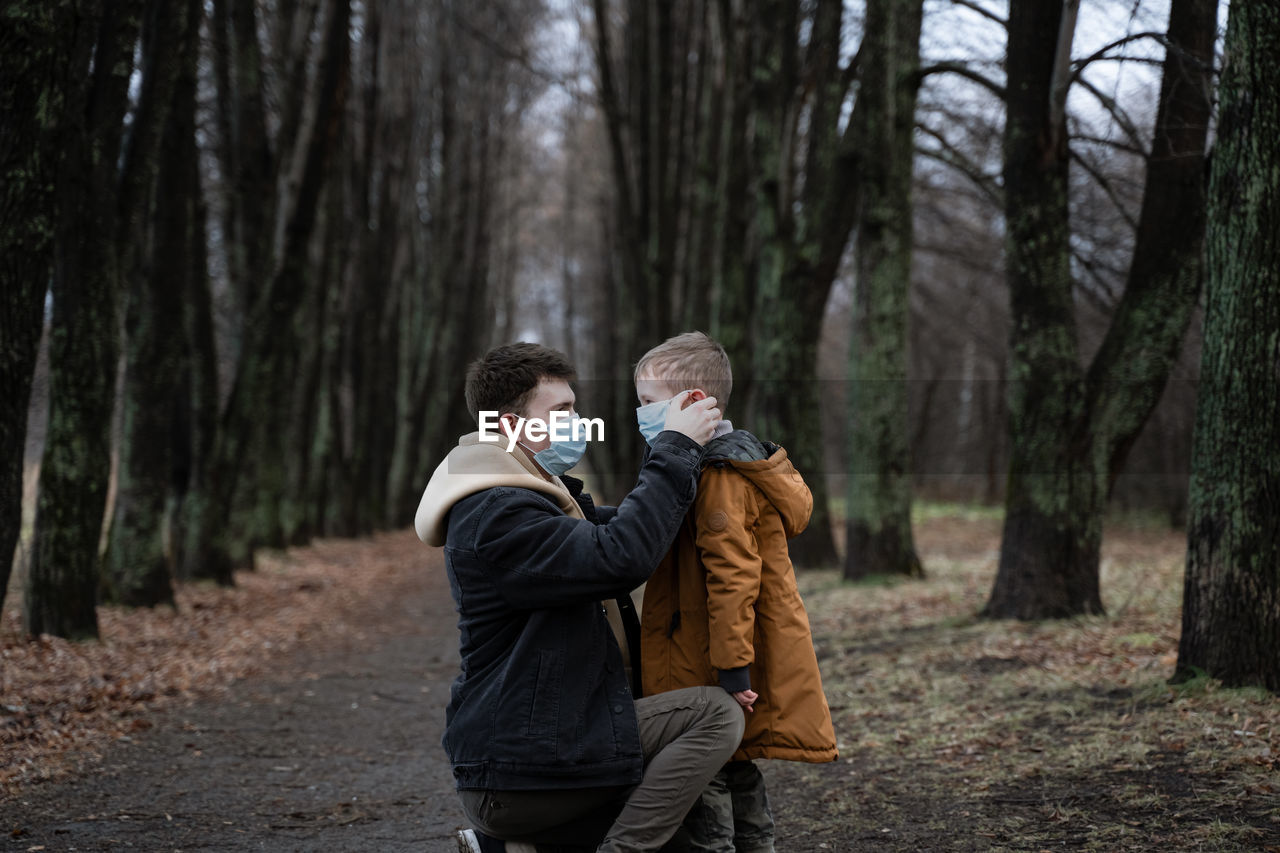 Father wearing mask to son in forest