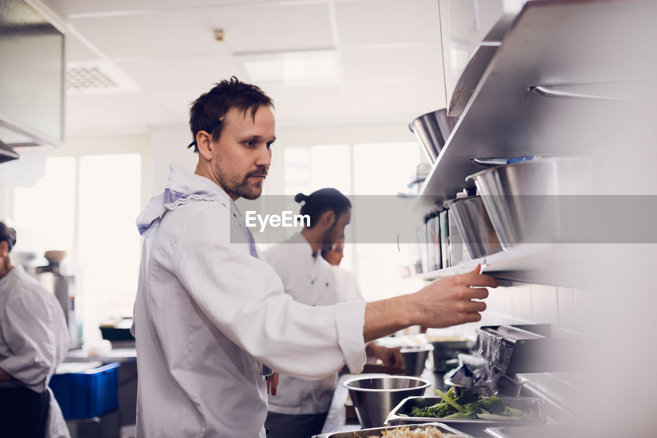 Young male chef reading order ticket in commercial kitchen