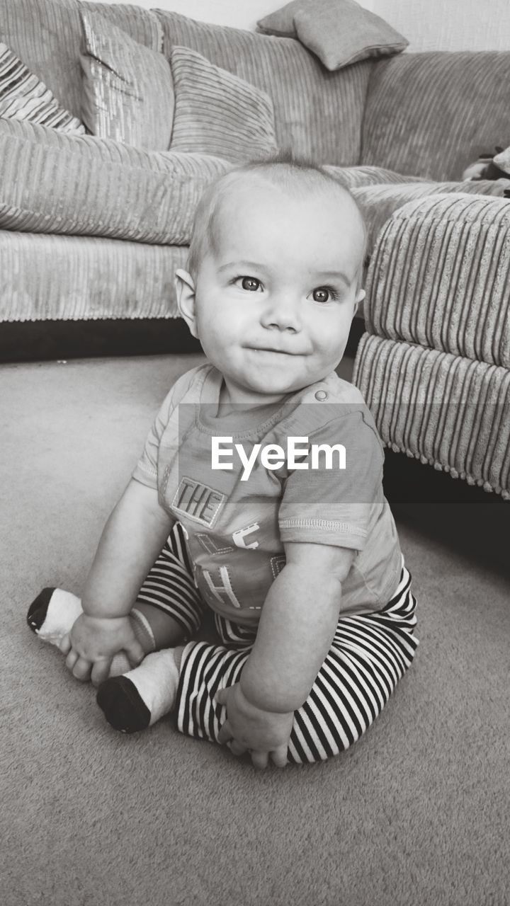 Close-up of baby boy looking away while sitting on floor