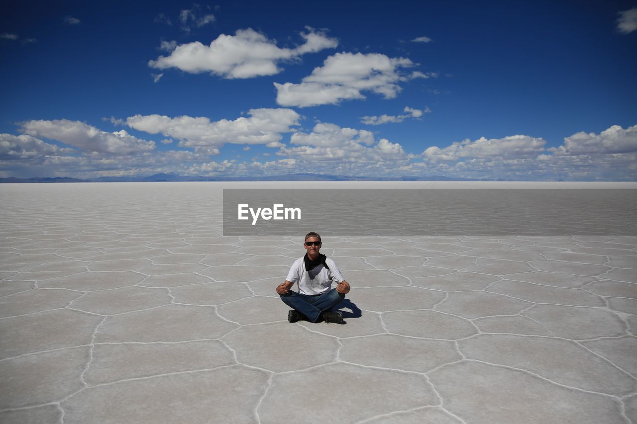 Portrait of man sitting on landscape against sky