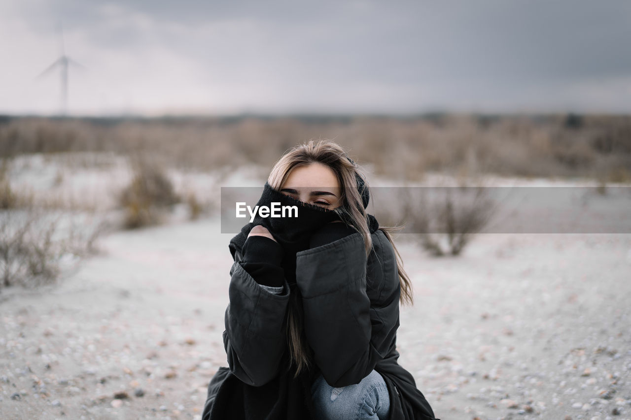 Portrait of woman standing on sand on the beach during winter