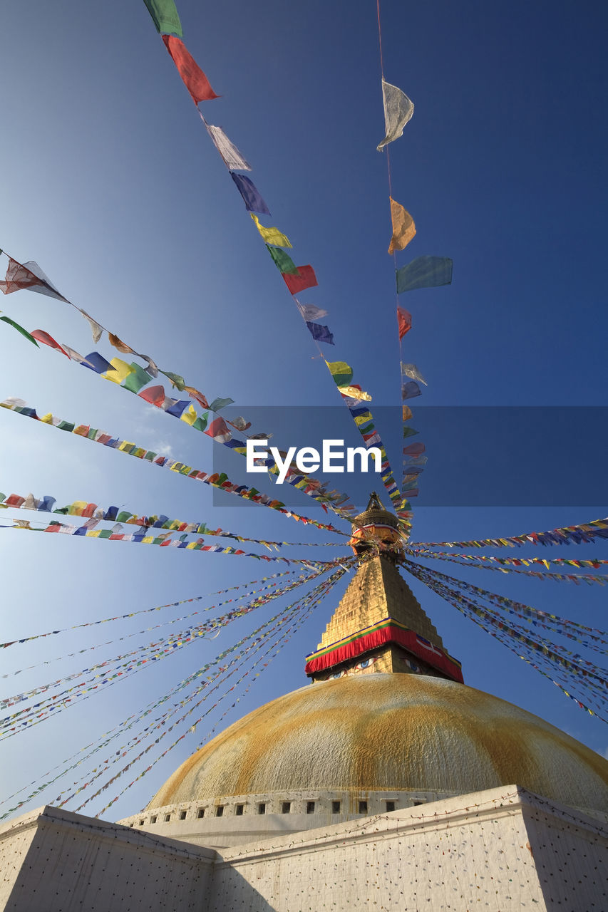 Nepal, bagmati province, kathmandu, prayer flags hanging from top of boudhanath stupa