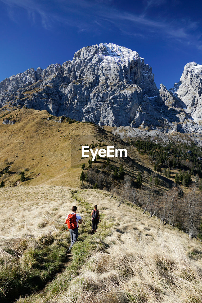 PEOPLE BY MOUNTAIN AGAINST SKY