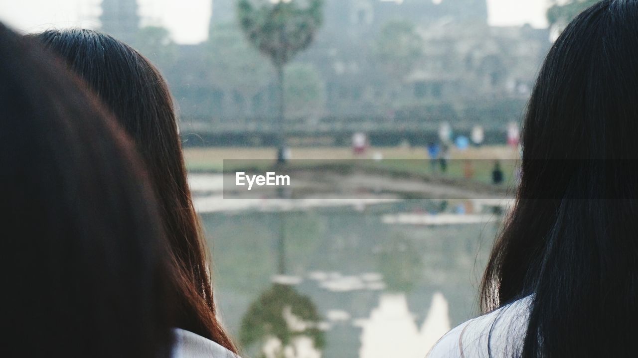 Close-up of women standing against lake