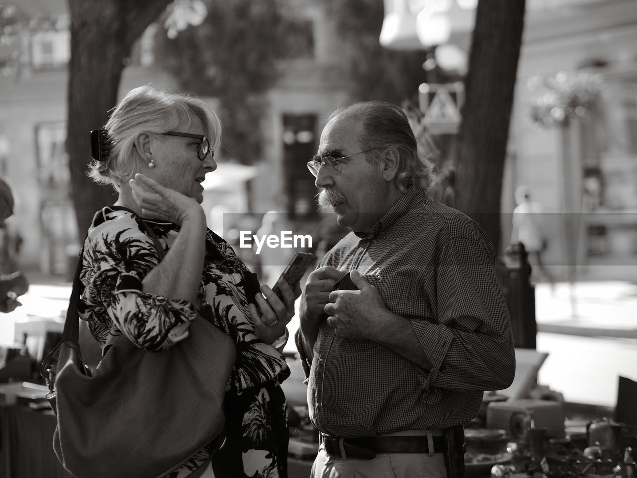 REAR VIEW OF COUPLE KISSING WITH PEOPLE ON THE BACKGROUND