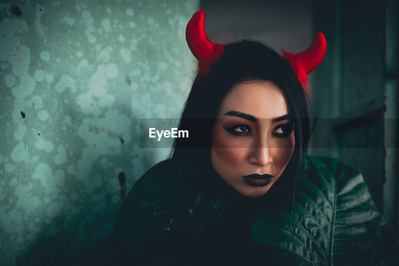 Close-up of young woman wearing spooky make-up and horned headband