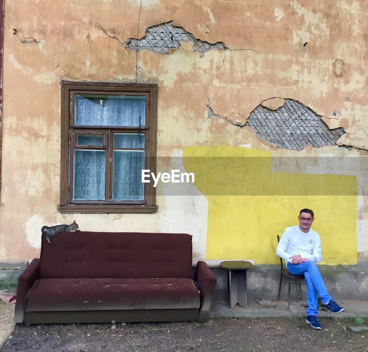 FULL LENGTH PORTRAIT OF MAN STANDING AGAINST WALL OF BUILDING