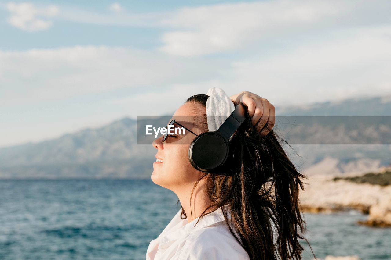 PORTRAIT OF WOMAN WITH SUNGLASSES AGAINST SEA