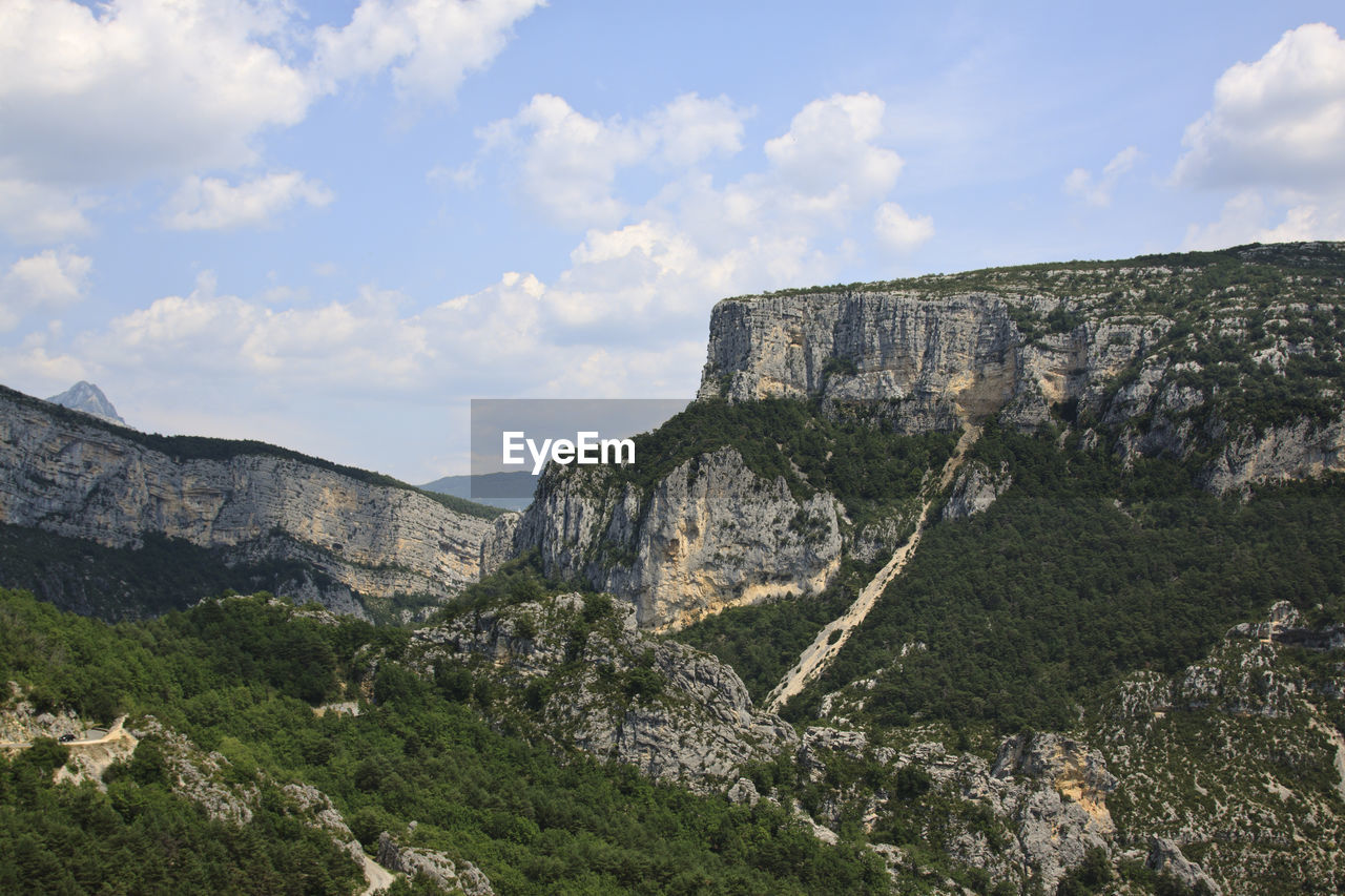 Panoramic view of rocky mountains against cloudy sky